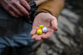 Hand holding a set of three Air-Lock Center Lock (3 Pack) fishing bobbers in bright orange, yellow, and white colors with textured surfaces, used for fishing tackle.