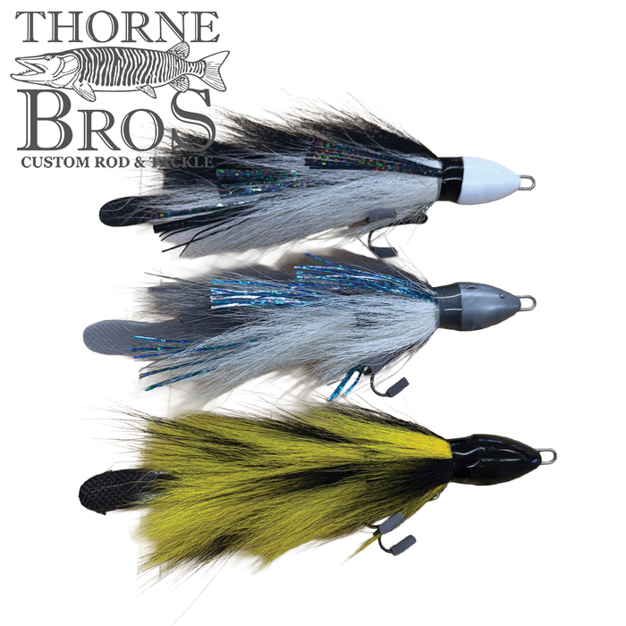 Three fishing lures with feather and synthetic skirt patterns in black and white, blue and silver, and yellow and black, each with a weighted head, displayed together as Baby Beaver Micro Beaver - Deep.