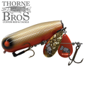 Bomb Squad Double Tap Flap Tail fishing lure featuring a detailed yellow and orange body with treble hooks and dual metallic spinner blades for enhanced movement in water.