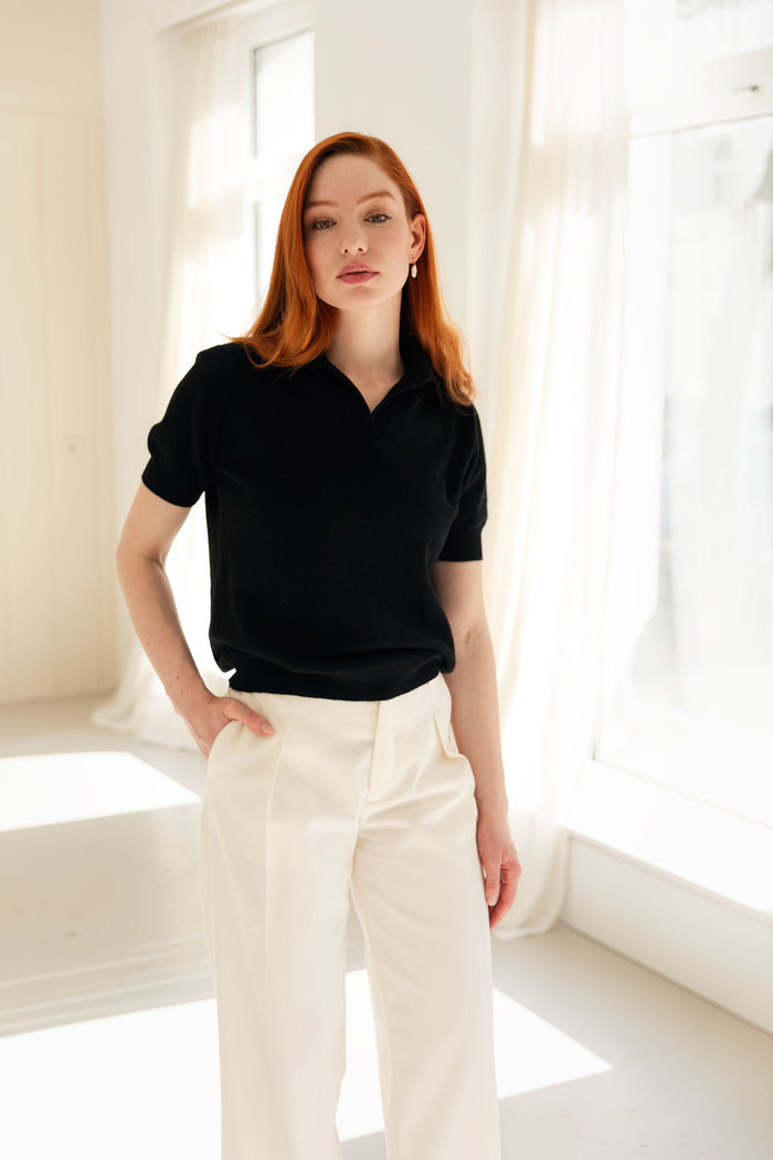 Woman wearing a 100% Mongolian cashmere polo shirt and white pants.