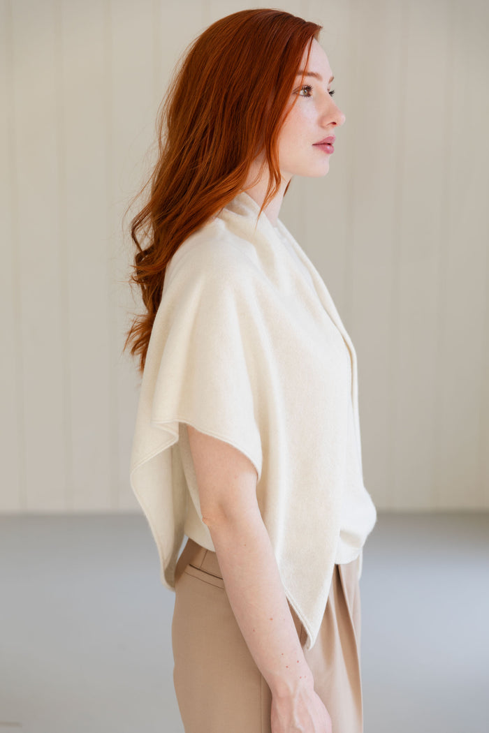 Woman wearing a white cashmere triangle scarf against a neutral background