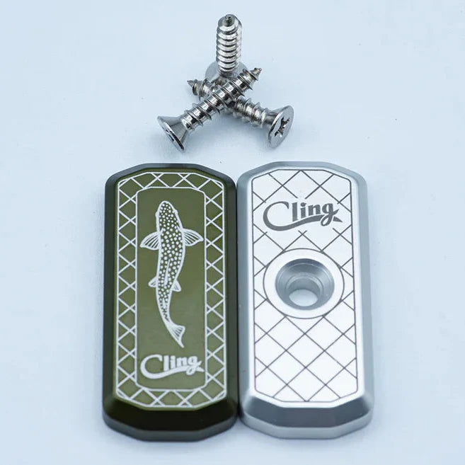 Cling Mag Grab Net Rack shown in green and silver metal plates with engraved fish design and logo, accompanied by three mounting screws for fishing tackle organization.