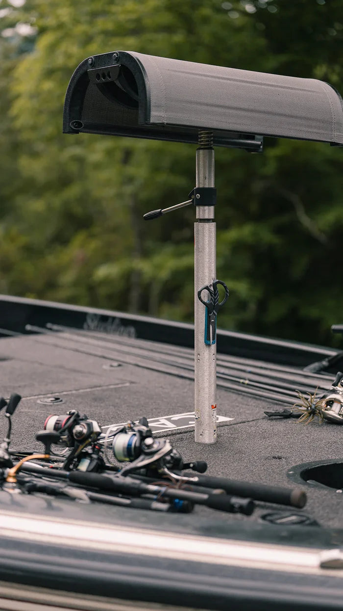 Cling Tool Stick Mini attached to a boat seat post with black fishing scissors hanging on it, fishing rods and reels positioned on the boat deck in the background.