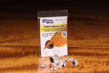 Clear plastic Fish-Skull Fish-Mask fishing lure eyes displayed in front of packaging on a wooden surface, designed for use with fishing tackle and fly fishing gear.