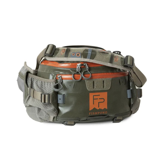 Fishpond Stormshadow Lumbar Pack in green and tan with multiple zippered compartments, adjustable strap, and durable material designed for convenient fishing tackle storage.