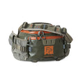 Fishpond Stormshadow Lumbar Pack in green and tan with multiple zippered compartments, adjustable strap, and durable material designed for convenient fishing tackle storage.