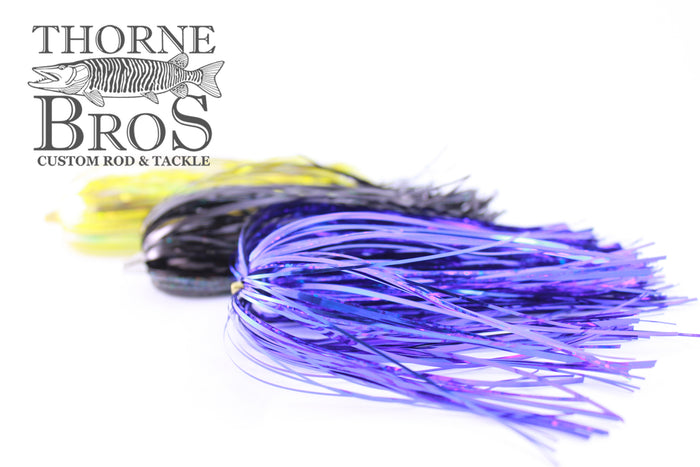 Close-up of colorful Leaders & Lures Tinsel Skirt fishing lures in purple, black, and yellow designed for musky fishing, displayed on a white background.