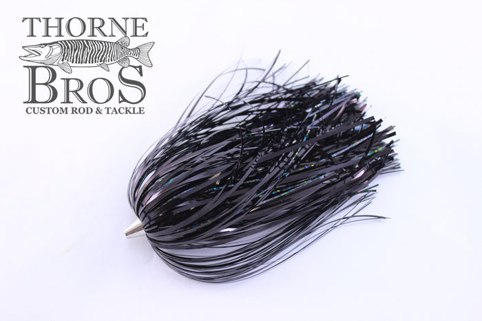 Close-up of a black Leaders & Lures Tinsel Skirt fishing lure with reflective tinsel strands, designed for use with fishing tackle and custom rods at Thorne Bros.