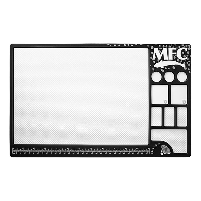 MFC Fly Tying Mat with black frame featuring multiple compartments for organizing fly tying materials, a textured work surface, measurement rulers, and logos, designed for fishing tackle.
