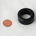 Minn Kota FERRITE, STEWARD P/N: 470085-1 is a small black cylindrical ferrite ring shown next to a penny for size comparison, used in fishing tackle and marine electronics.