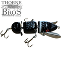 Musky Safari Franken Spitz Jr. black segmented musky fishing lure with treble hooks and spinner blade shown beside Thorne Bros Custom Rod and Tackle logo