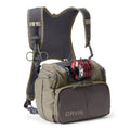 Orvis Chest Pack in olive and dark gray, featuring multiple zippered compartments, adjustable padded straps, and attached fishing line spool for organizing fishing tackle and gear.