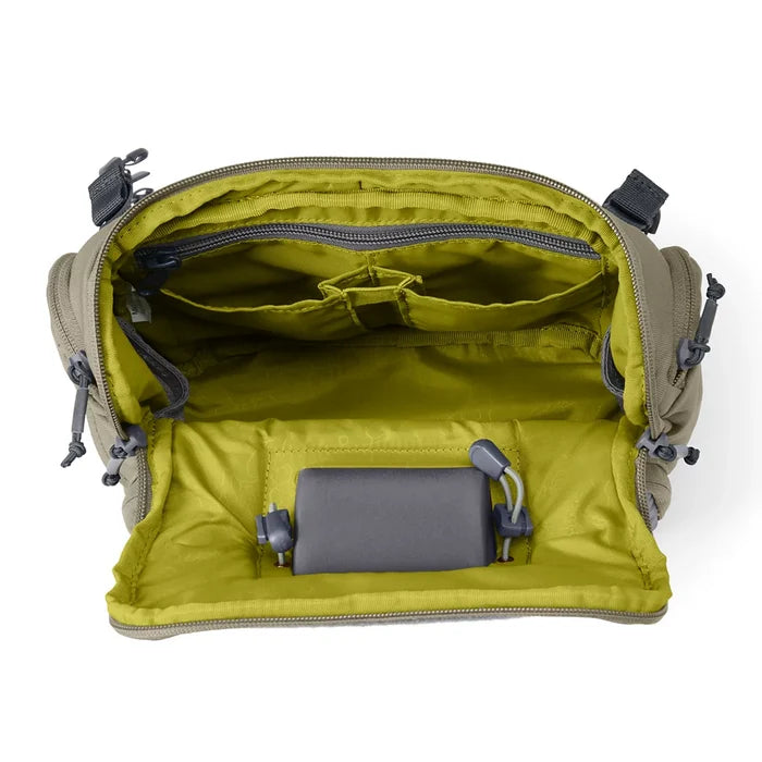 Orvis Chest Pack open to show multiple compartments and organizational pockets with a yellow interior lining, designed for fishing tackle and gear storage.