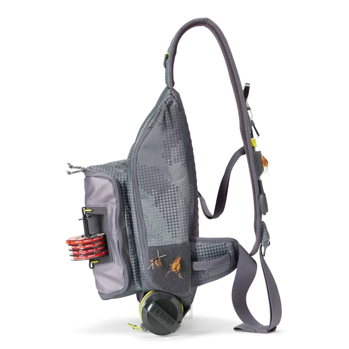 Orvis Sling Pack in gray with multiple compartments, featuring fishing tackle attachments, adjustable straps, and compact design ideal for carrying fishing gear and lures.