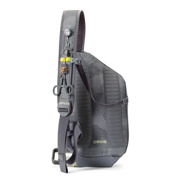 Orvis Sling Pack in dark gray featuring a single padded shoulder strap with clips, loops, and attachments for fishing tools, designed for lightweight fishing tackle organization.