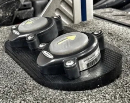 Close-up of the black Precision Sonar Stomp Station for Power Pole and Minn Kota Raptor - Double PN:SWS-DBLE mounted on a textured gray surface, showing two circular stomp pads with yellow arrows.