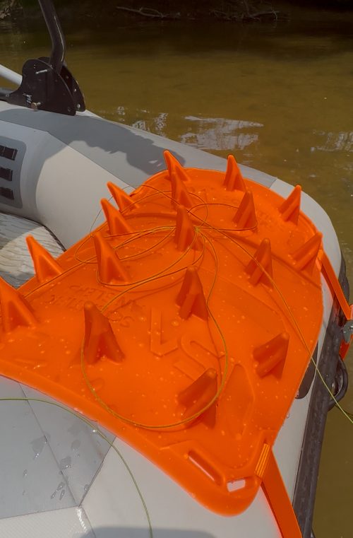 Scientific Anglers Launch Pad Drift, a bright orange, textured casting platform designed to stabilize and organize fishing rods and lines on a boat surface, shown with fishing line.
