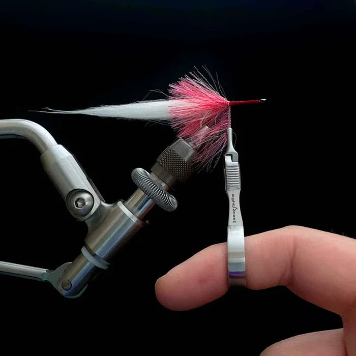 Sight Cast Palmering Pliers gripping a pink and white fishing lure securely, shown in use for fly fishing tackle preparation against a dark background.