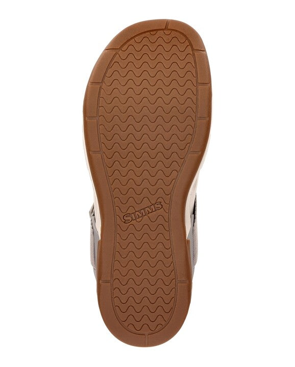 Close-up view of the brown rubber sole of the Simms Drifter shoe featuring a wave-pattern tread and the Simms logo embossed in the center for enhanced traction.