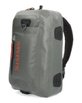 Simms Dry Creek Z Sling Pack in gray with orange zipper pull and logo, featuring durable fabric, multiple compartments, and padded adjustable sling strap for fishing tackle storage.