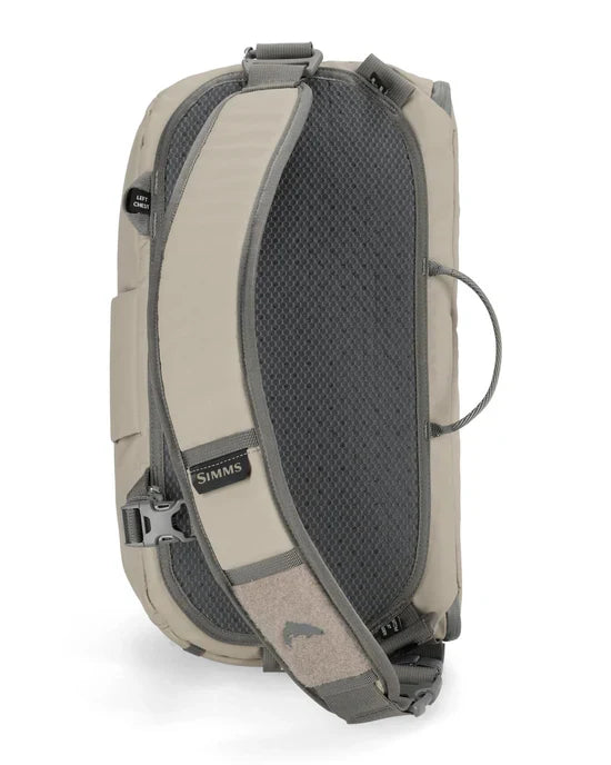 Simms Headwaters Sling Pack shown from the back, featuring padded adjustable shoulder strap with mesh back panel, light tan and gray durable fabric designed for fishing tackle and gear storage.