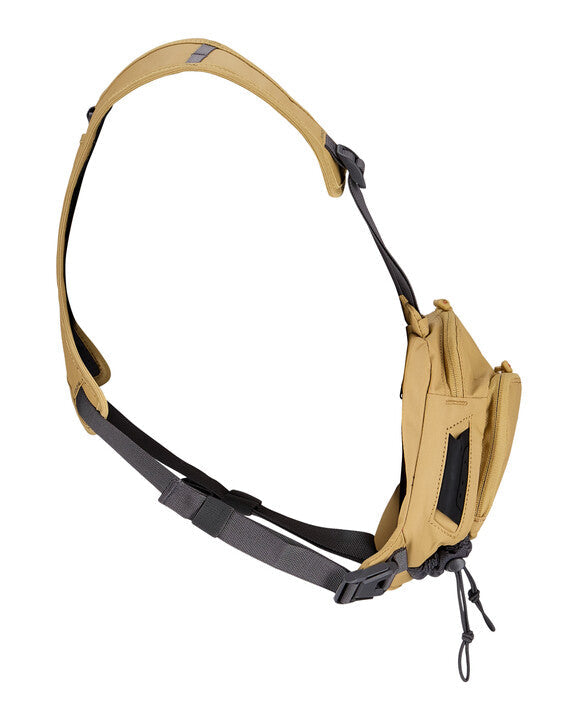 Simms Tributary Chest Pack in tan with adjustable padded shoulder strap, multiple zippered compartments, and durable fabric designed for fishing tackle organization and easy access.