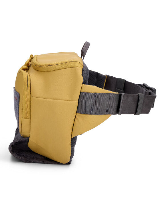 Simms Tributary Hip Pack in yellow and gray with multiple zippered compartments and adjustable waist strap designed for convenient fishing tackle storage.