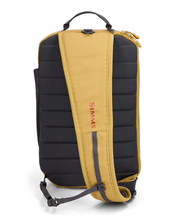 Simms Tributary Sling Pack shown from the back with padded black and mustard yellow adjustable single shoulder strap, breathable mesh backing, and top carrying handle.
