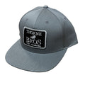 Gray baseball cap with a black and white embroidered patch reading "Thorne Bros Fly Fishing," featuring a structured crown and flat brim, called Thorne Bros Fly Fishing Logo Richardson 255 Flint Grey.