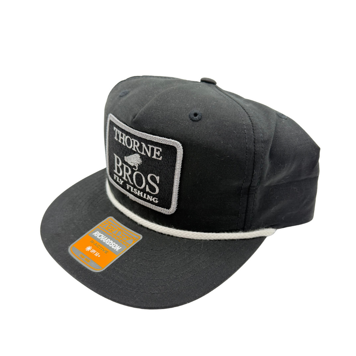 Thorne Bros Fly Fishing Logo Richardson Umpqua Gramps 256 Hat Black/White featuring black fabric, white embroidered logo patch, structured crown, and flat brim with a white rope detail.