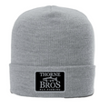 Light gray knit beanie with a folded cuff featuring a black patch with white text and a trout graphic, labeled Thorne Bros. Fly Fishing, Thorne Bros. Fly Fishing Trout Logo Cuff Beanie.
