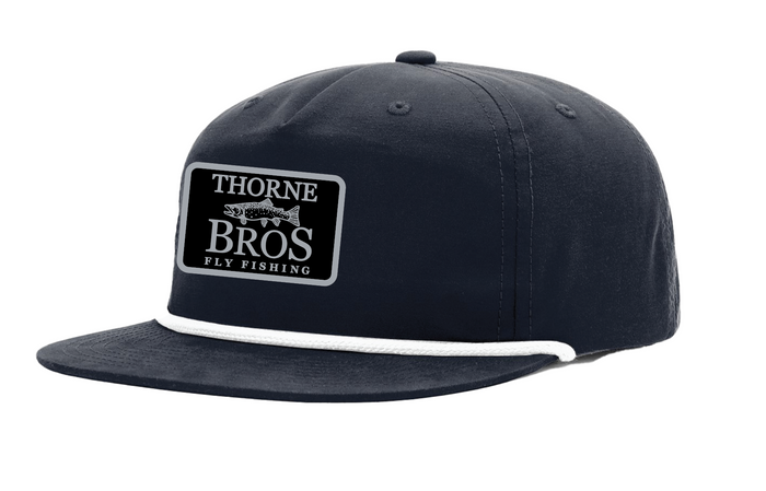 Thorne Bros Fly Fishing Trout Logo Richardson Umpqua Gramps 256 Hat Navy/White with navy crown, white embroidered trout logo patch, flat brim, and white rope accent on front above brim.