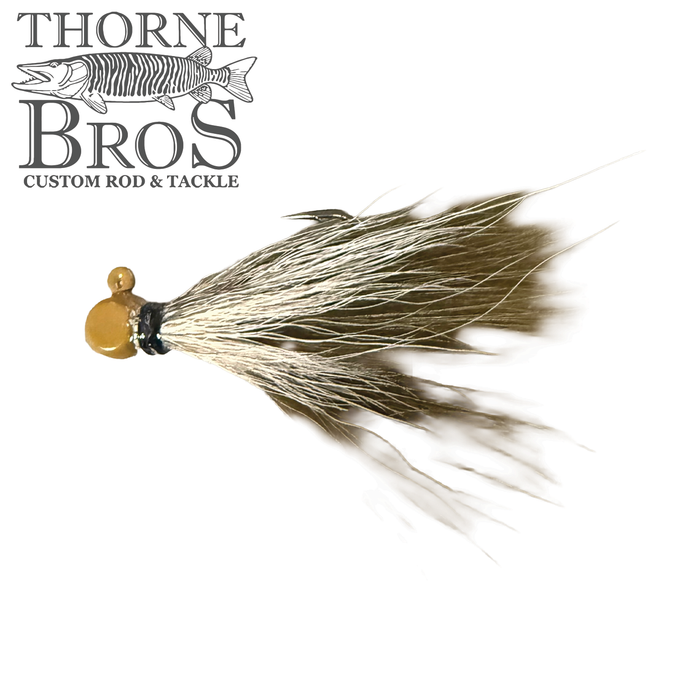 Thorne Brothers Hair Jig - Finesse features a small, detailed fishing lure with a gold-colored jig head and natural, flowing hair strands designed for finesse fishing techniques.