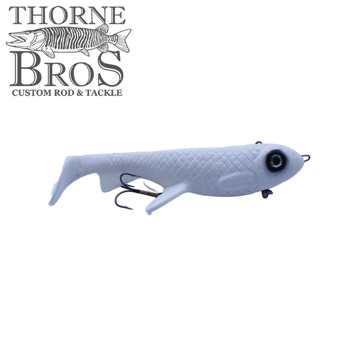 White soft plastic fishing lure with textured body, large black eye, and two treble hooks, identified as Trophy Systems Bait Co. 10" Osprey for musky fishing.