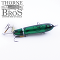 Green and black segmented fishing lure with treble hooks and a metal spinner blade, designed for musky fishing, labeled as Ty Sennett Pacemaker - Wood.