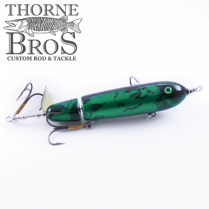Green and black segmented fishing lure with treble hooks and a metal spinner blade, designed for musky fishing, labeled as Ty Sennett Pacemaker - Wood.