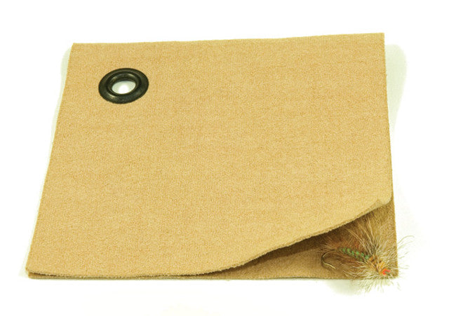 Umpqua Wonder Cloth Dry Fly Patch in tan color with a metal grommet, shown folded with several dry fly fishing lures attached, designed for organizing fishing tackle.