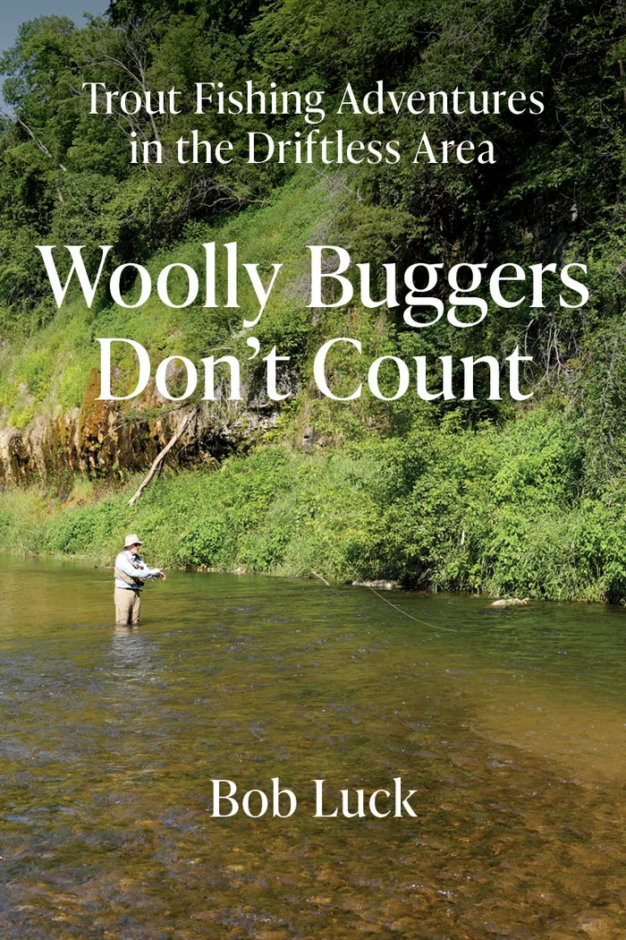 A person fly fishing in a clear river surrounded by lush green trees and rocky cliffs, with the text "Trout Fishing Adventures in the Driftless Area Wooly Buggers Don't Count Bob Luck" overlayed.